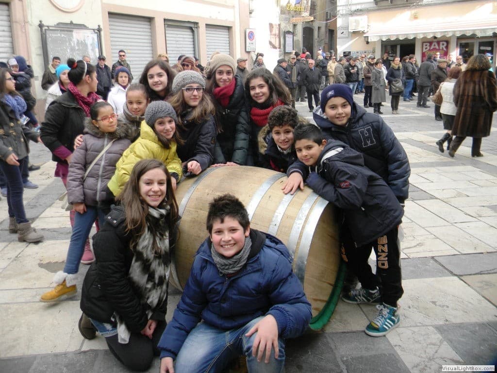 Un gruppo di bambini e ragazzi riuniti attorno alla grande botte, con il pubblico sullo sfondo