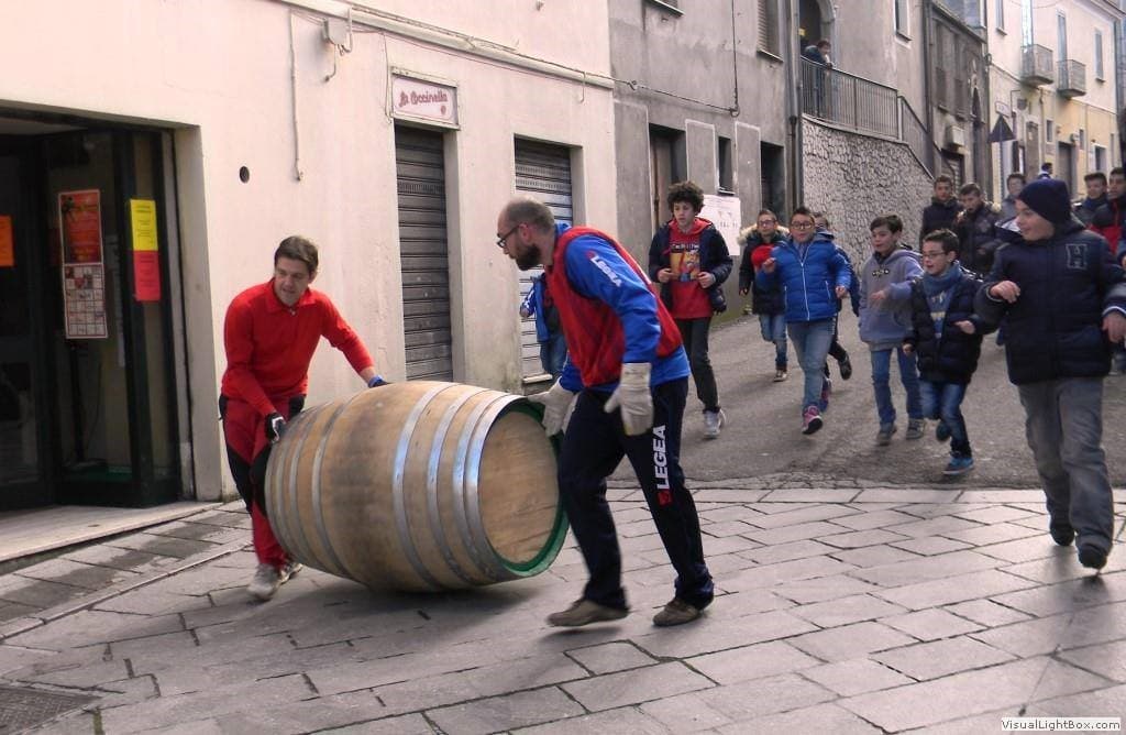 Due partecipanti spingono una botte lungo una strada di Mormanno, seguiti dai ragazzi